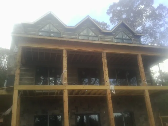 Dormers and porch framing on a large log home under construction — Roof Coating work by our crew in Welch