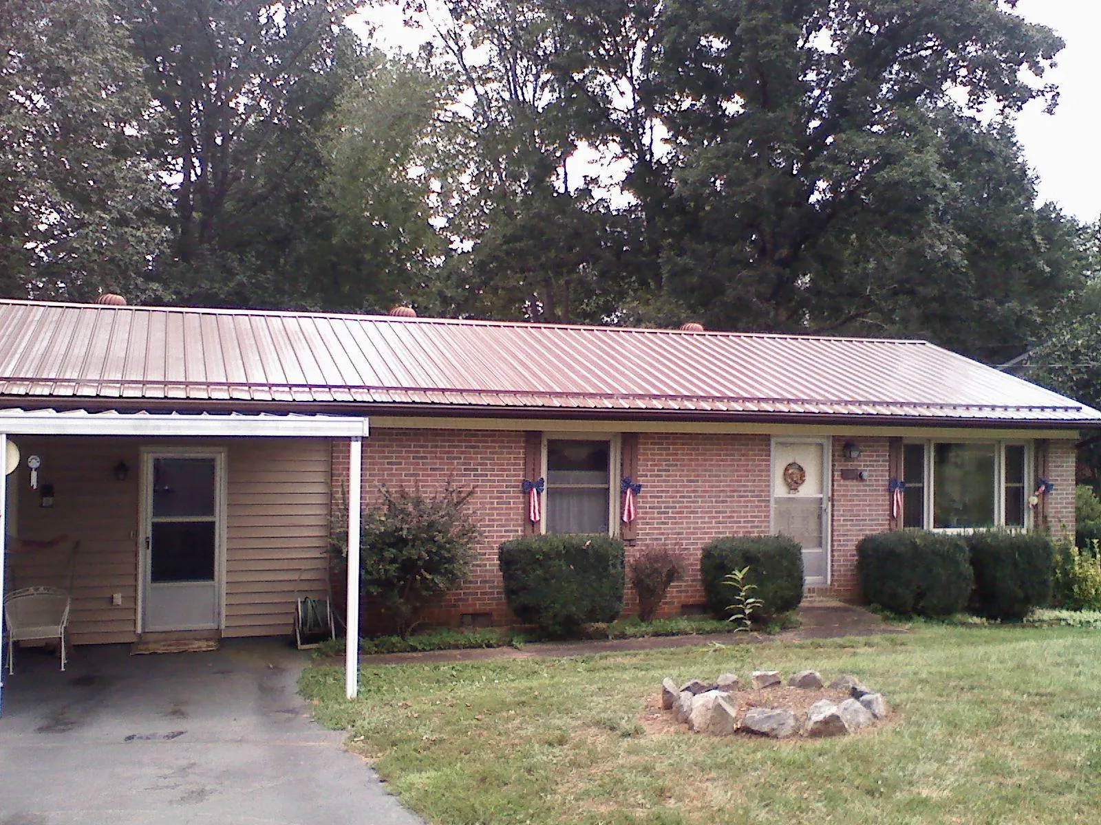 Bronze metal roof and carport on a brick ranch home — Roof Repair work by our crew in Welch